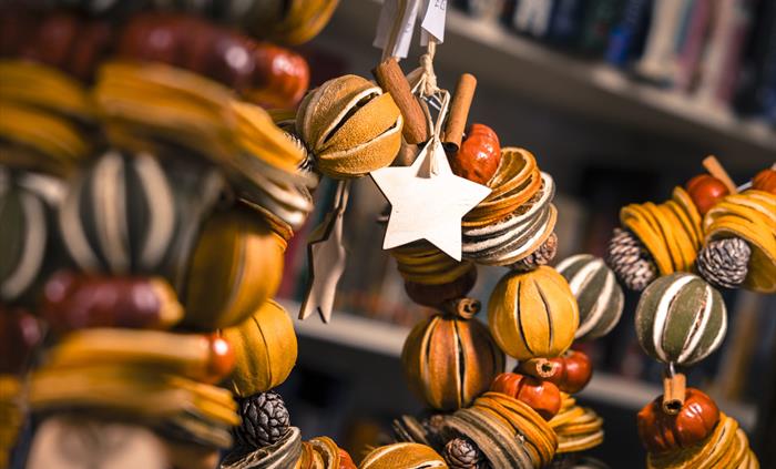 Close up of rustic Christmas wreaths made of dried oranges, pinecones and cinnamon.